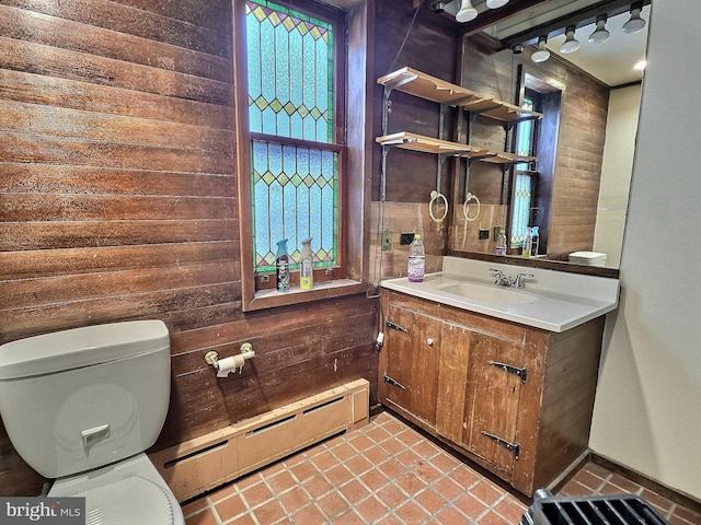 half bathroom featuring tile patterned flooring, a baseboard radiator, toilet, and wood walls