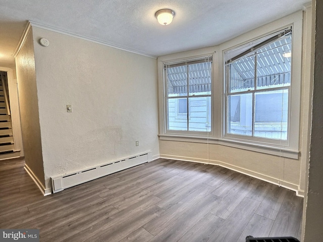 spare room with crown molding, a textured wall, a baseboard heating unit, and dark wood-style floors