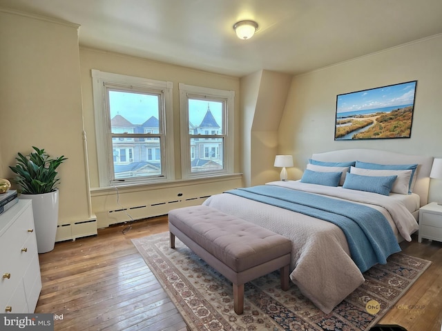 bedroom with ornamental molding, a baseboard radiator, baseboard heating, and hardwood / wood-style floors