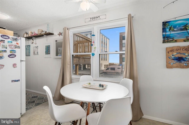 dining space with baseboards, a ceiling fan, and a textured ceiling