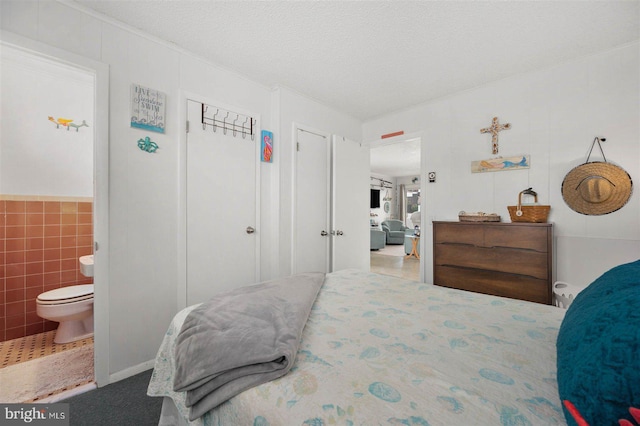 bedroom with connected bathroom and tile walls
