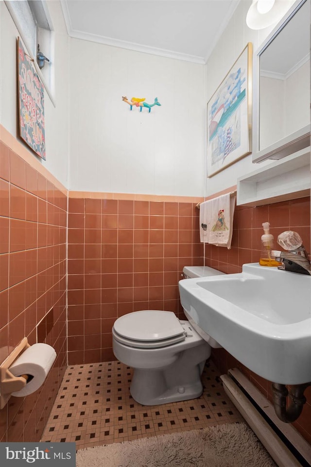 bathroom with crown molding, toilet, and tile walls