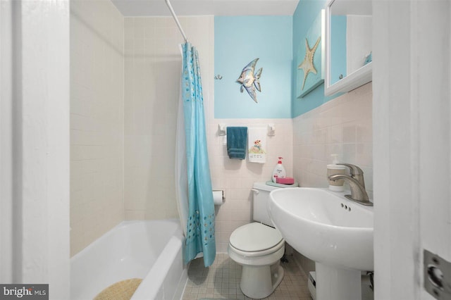 bathroom featuring tile walls, a sink, tile patterned floors, toilet, and shower / tub combo with curtain