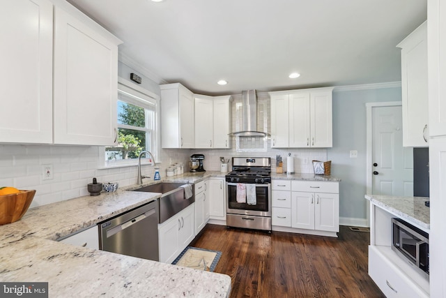 kitchen featuring a sink, wall chimney exhaust hood, stainless steel appliances, white cabinets, and ornamental molding