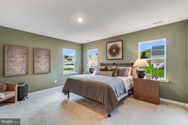 bedroom with baseboards, multiple windows, light carpet, and visible vents
