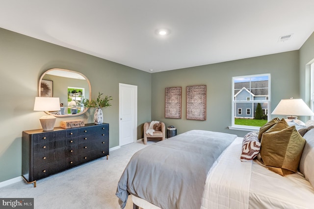 carpeted bedroom featuring visible vents, baseboards, and multiple windows