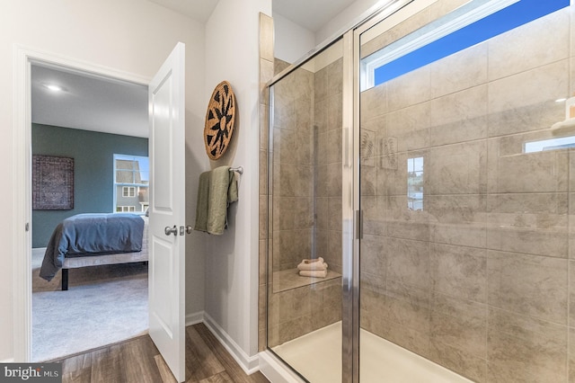 bathroom featuring baseboards, ensuite bath, wood finished floors, and a shower stall