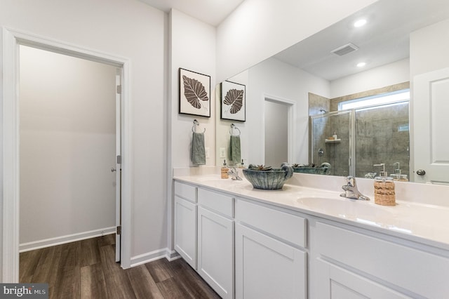 full bathroom featuring visible vents, a sink, wood finished floors, and a shower stall