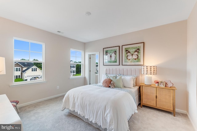 bedroom with baseboards, light carpet, and visible vents