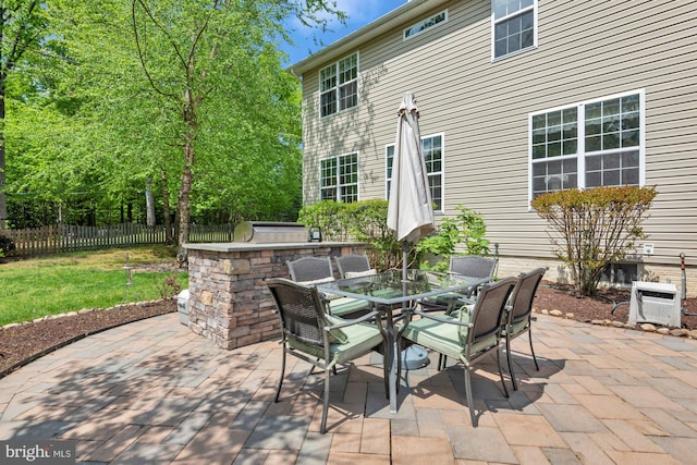 view of patio with an outdoor kitchen, fence, and outdoor dining space