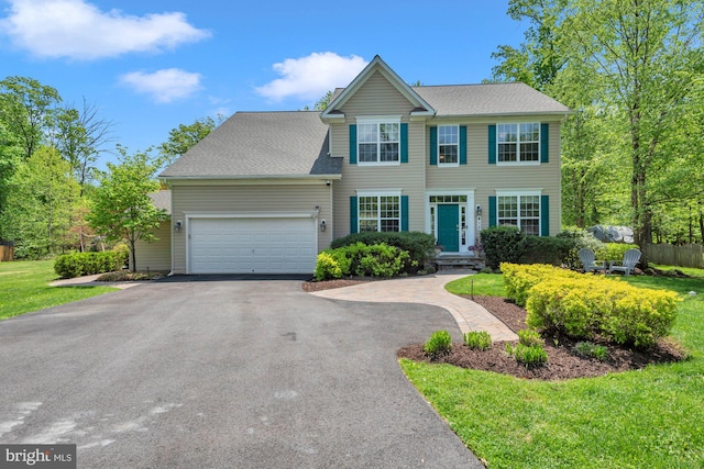 colonial-style house with an attached garage, driveway, and a front yard