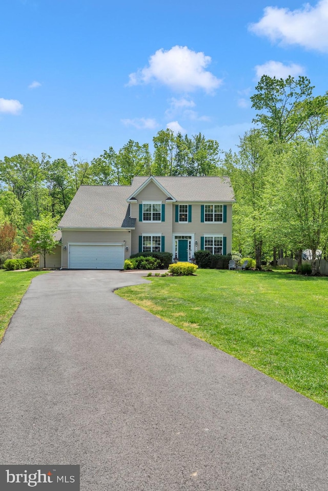 colonial house featuring driveway, a front yard, and a garage