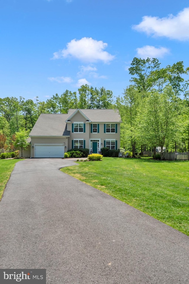 colonial inspired home featuring an attached garage, a front lawn, aphalt driveway, and fence