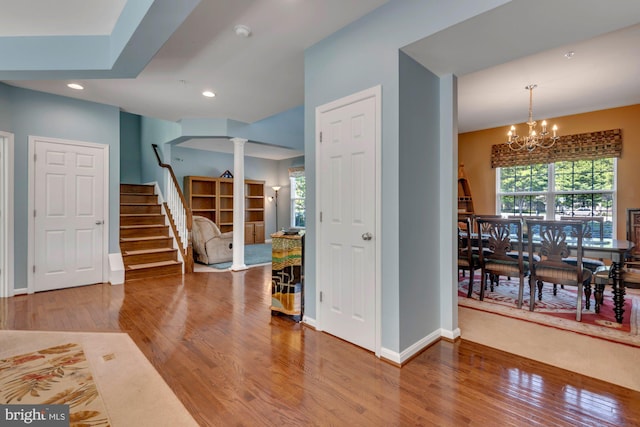 entrance foyer with an inviting chandelier, wood finished floors, stairway, ornate columns, and recessed lighting