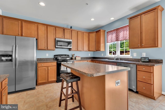 kitchen featuring a kitchen island, appliances with stainless steel finishes, dark countertops, a sink, and light tile patterned flooring