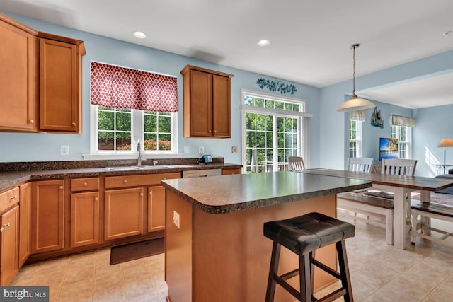 kitchen featuring a sink, a kitchen breakfast bar, brown cabinets, and dark countertops
