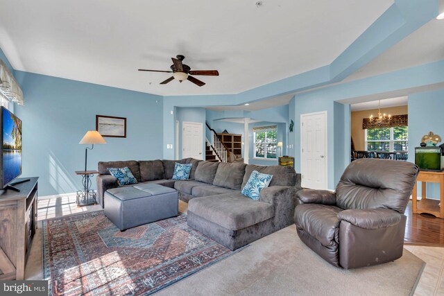 living room with stairway and ceiling fan with notable chandelier