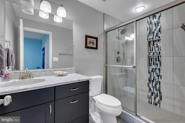 bathroom featuring vanity, a shower stall, and toilet