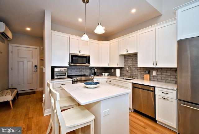 kitchen with a sink, a kitchen island, stainless steel appliances, and white cabinetry