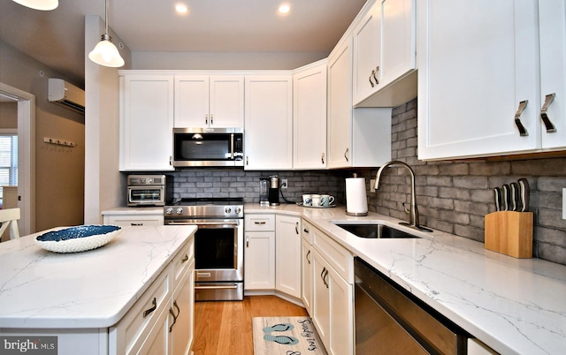 kitchen featuring white cabinets, a sink, light wood-style flooring, stainless steel appliances, and a wall unit AC