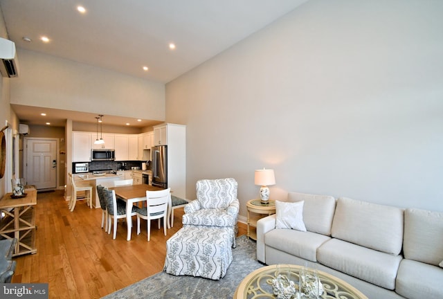 living area with baseboards, recessed lighting, light wood-style flooring, and a towering ceiling