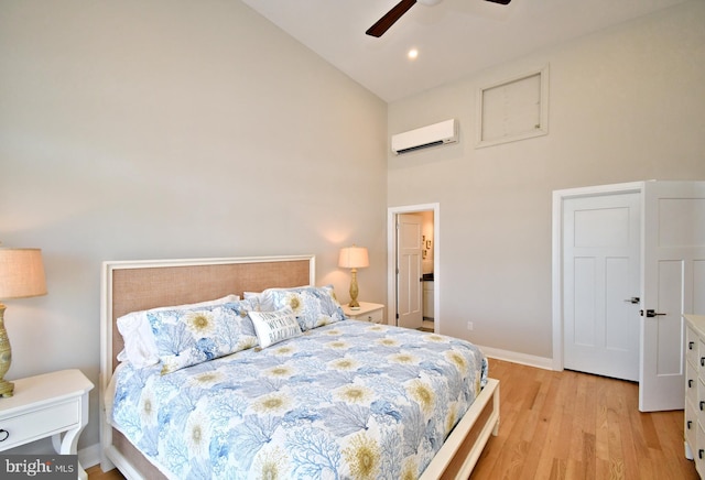 bedroom with ceiling fan, a wall mounted air conditioner, high vaulted ceiling, baseboards, and light wood finished floors