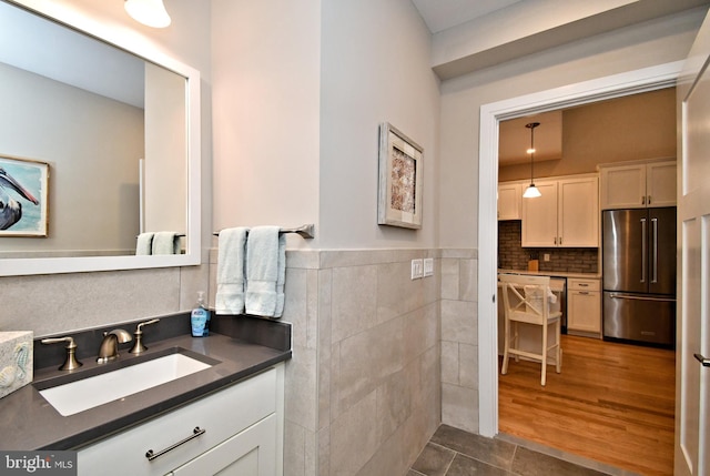 bathroom featuring tile patterned floors, tile walls, wainscoting, and vanity