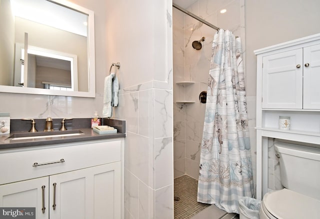 bathroom with vanity, a tile shower, and toilet