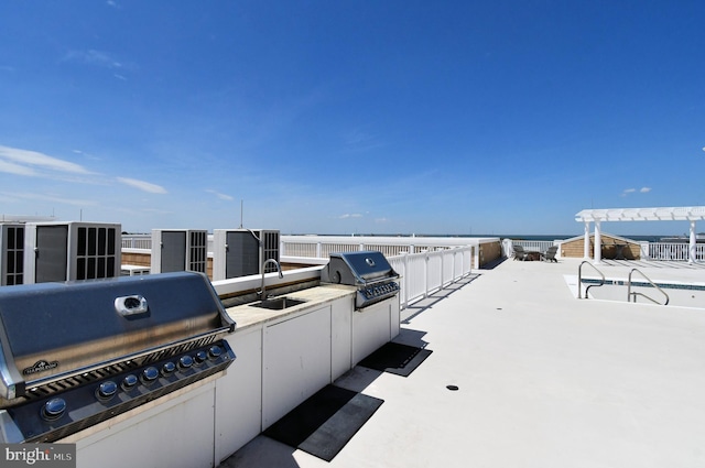 view of patio / terrace with an outdoor kitchen, a sink, a water view, and a grill