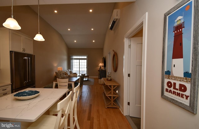 dining room with light wood-style floors, recessed lighting, baseboards, a wall unit AC, and lofted ceiling