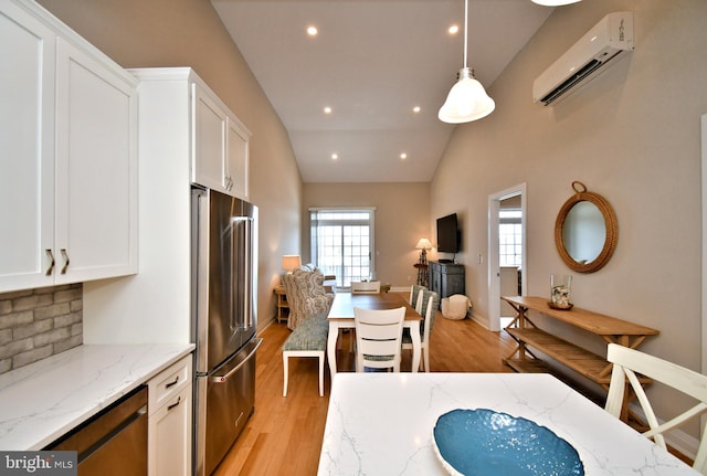 kitchen featuring light wood-style floors, freestanding refrigerator, an AC wall unit, and white cabinetry