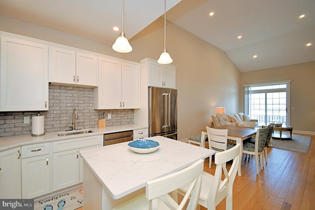 kitchen with a sink, white cabinetry, decorative backsplash, high quality fridge, and dishwashing machine