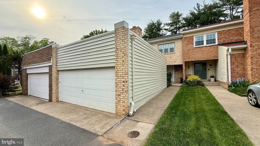 view of property featuring brick siding, a garage, and a chimney