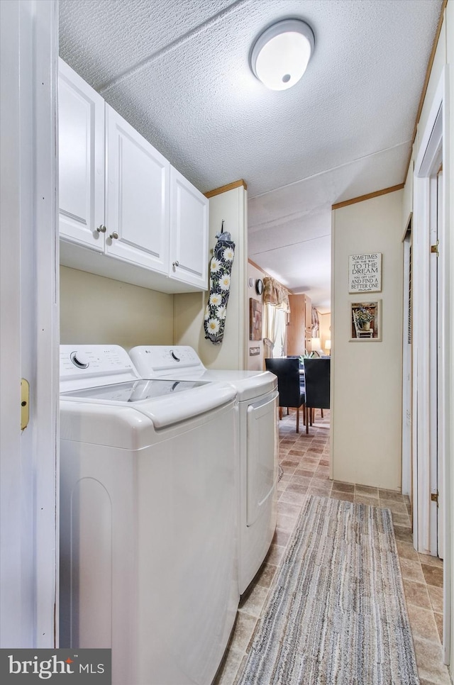 laundry area featuring a textured ceiling, cabinet space, and washing machine and clothes dryer