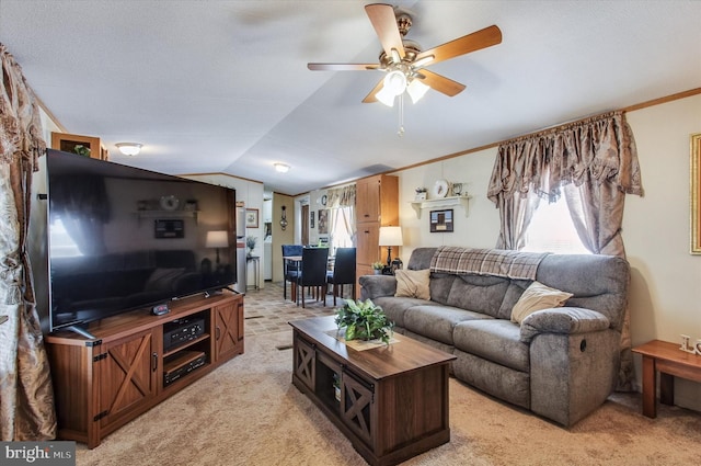 living area featuring plenty of natural light, a ceiling fan, vaulted ceiling, and light colored carpet