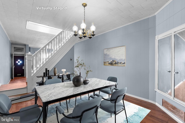 dining room featuring a chandelier, stairs, baseboards, wood finished floors, and ornamental molding
