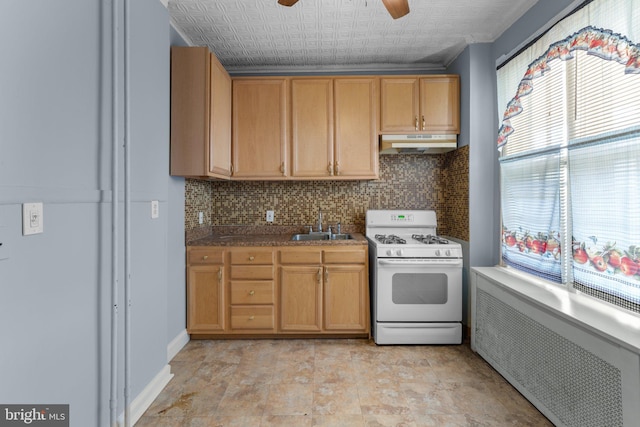 kitchen featuring white gas range oven, decorative backsplash, a ceiling fan, and under cabinet range hood