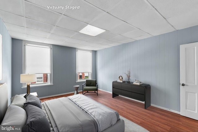 bedroom with baseboards, wood finished floors, and a paneled ceiling