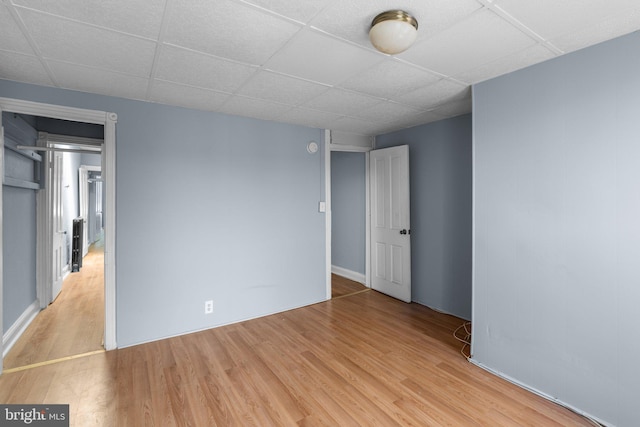 unfurnished bedroom with wood finished floors and a drop ceiling