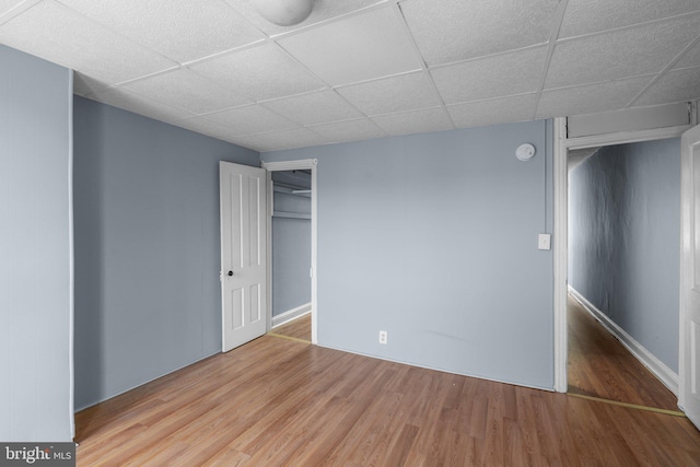 unfurnished bedroom featuring a closet, wood finished floors, and a paneled ceiling