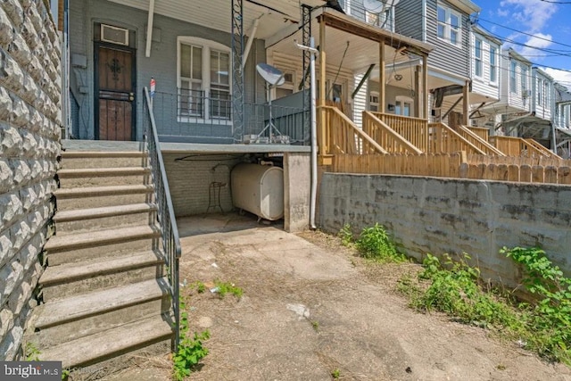 view of side of property with covered porch, brick siding, heating fuel, and stairs