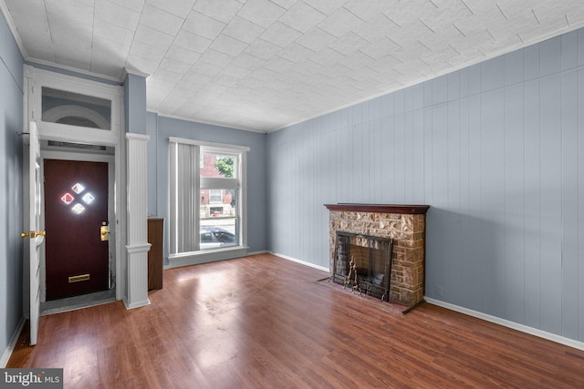 unfurnished living room with baseboards, a stone fireplace, and wood finished floors