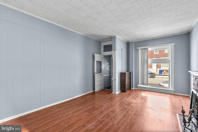 unfurnished living room featuring baseboards, ornamental molding, and wood finished floors