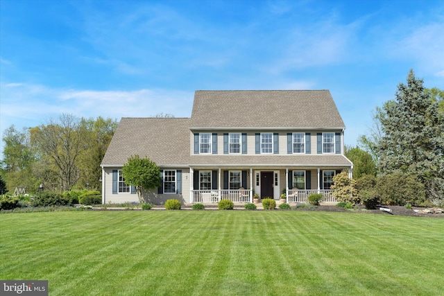 colonial-style house with covered porch, a shingled roof, and a front yard