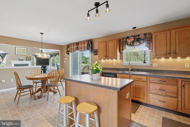 kitchen featuring plenty of natural light, a sink, a kitchen island, and dark countertops
