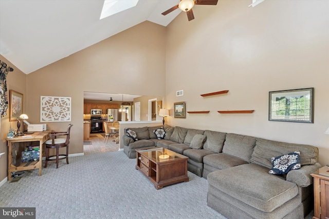 living room featuring ceiling fan, light carpet, high vaulted ceiling, a skylight, and visible vents
