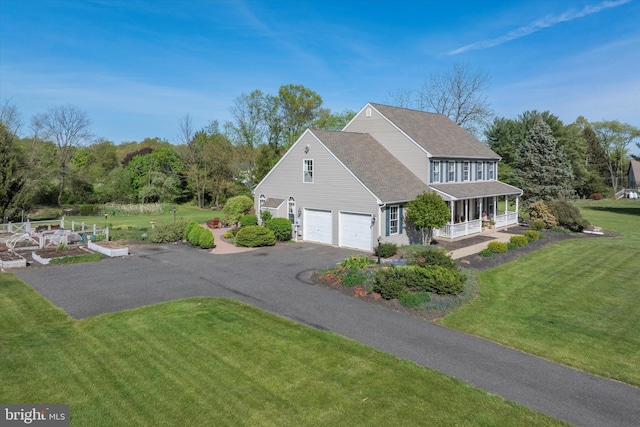 view of side of property with a shingled roof, an attached garage, a porch, a lawn, and driveway