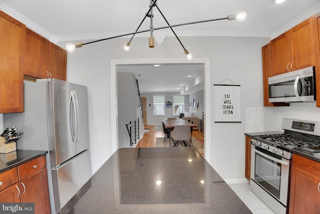 2019 Pemberton St, Philadelphia, PA 19146 - kitchen featuring appliances with stainless steel finishes, crown molding, brown cabinetry, dark stone countertops, and backsplash