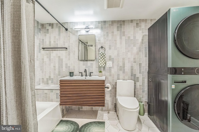 2019 Pemberton St, Philadelphia, PA 19146 - bathroom with stacked washing machine and dryer, tile walls, tile patterned flooring, shower / bath combo with shower curtain, and toilet