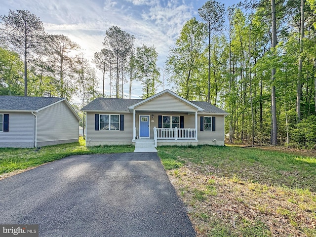 ranch-style home with a porch, driveway, and roof with shingles